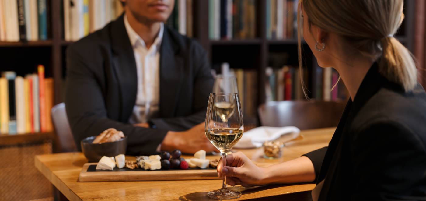 Two people enjoy a wine & cheese pairing in the library