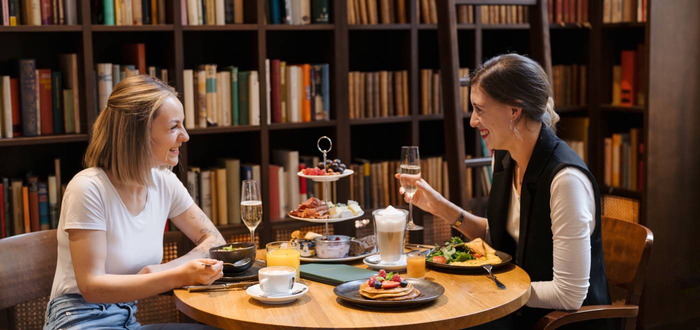 Two friends enjoy an extensive brunch in the library.
