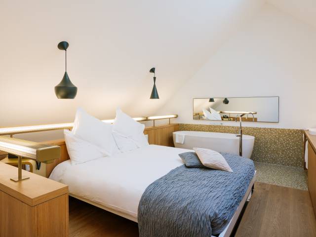 Doppelbett mit Badewanne in einem modernen Zimmer des B2 Hotels Zürich.