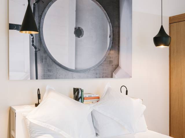 Cozy bed with picture from the brewery history and designer lamps