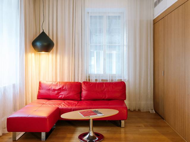 Rotes Ledersofa in der Ecke mit Lampe und Tisch