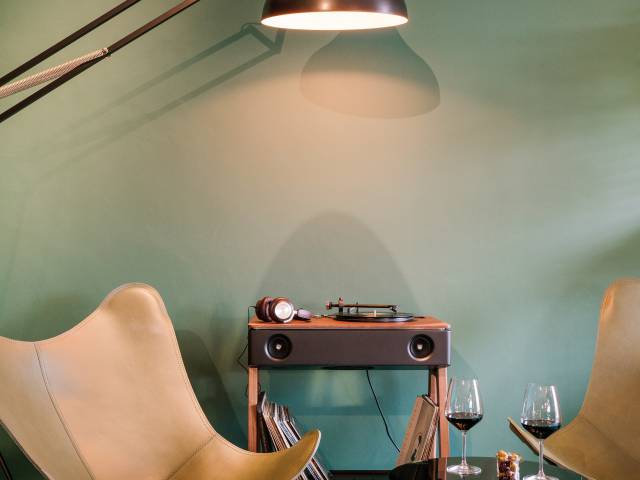 Old record player with comfortable armchairs and wine glasses on a coffee table in the B2 Hotel Zurich